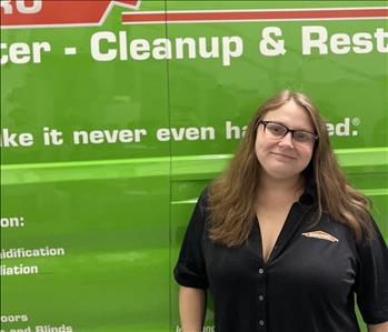A WOMAN IN FRONT OF A SERVPRO TRUCK.