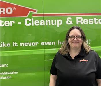 a woman in front of a green SERVPRO truck