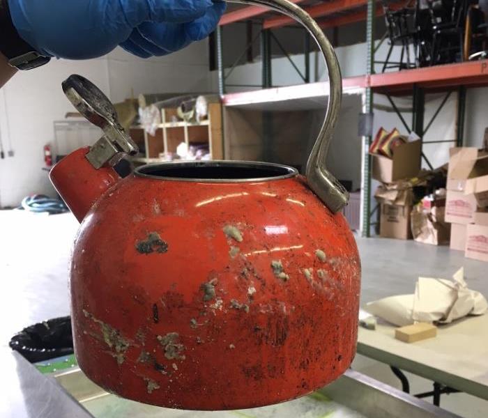 a tea pot with smoke and soot damage