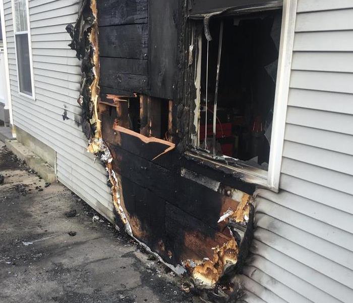 the exterior of a home with charred siding and an exposed hole